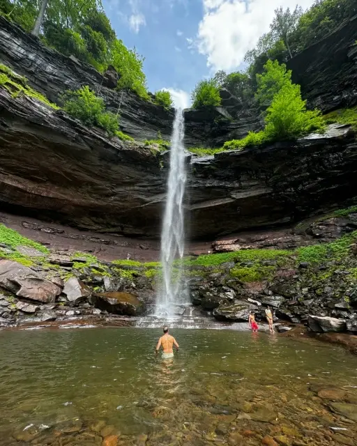 Swimmers in a natural pool below a waterfall