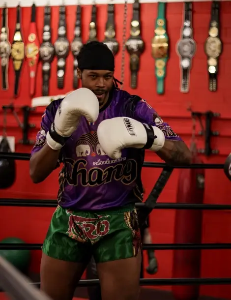 Muay Thai fighter training in a gym hung with championship belts
